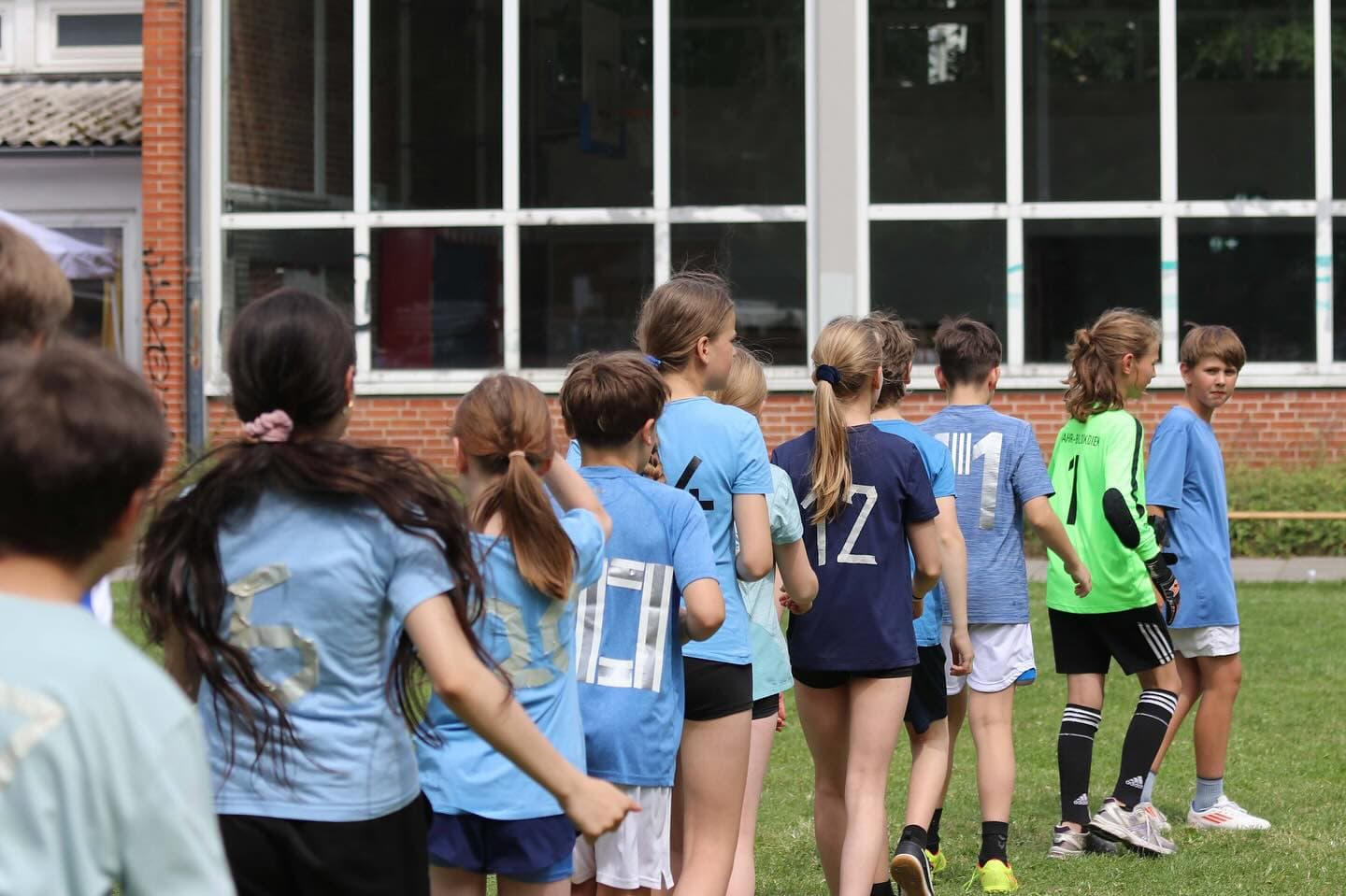 Einlauf des Teams in blauen Trikots auf den Rasenplatz.